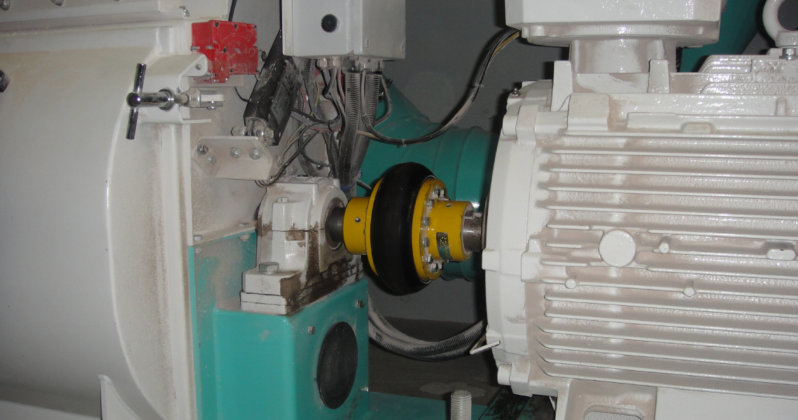 Antares AT flexible coupling installed on a hammer mill drive system in the agribusiness sector, connecting the electric motor to the gearbox.