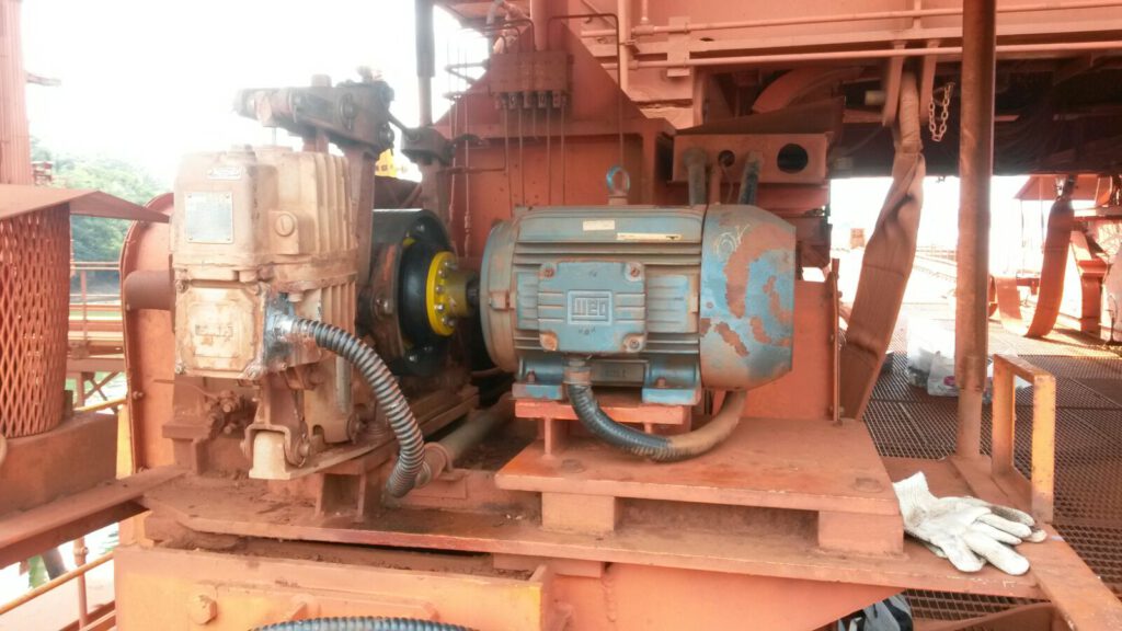 Motor elétrico com acoplamento flexível de pneu, acoplados a redutor industrial em ambiente de mineração, ilustrando práticas de manutenção e alinhamento que mostram como melhorar o desempenho do motor.