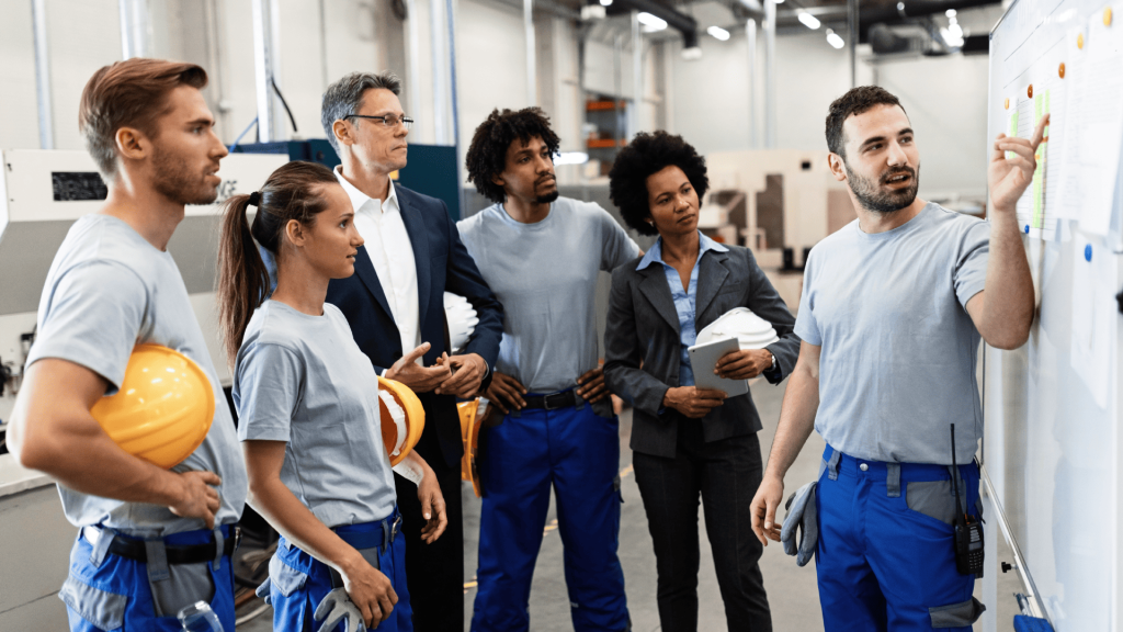 Grupo de técnicos e gestores em reunião dentro da fábrica, avaliando planos de trabalho para melhorar a produtividade na manutenção.
