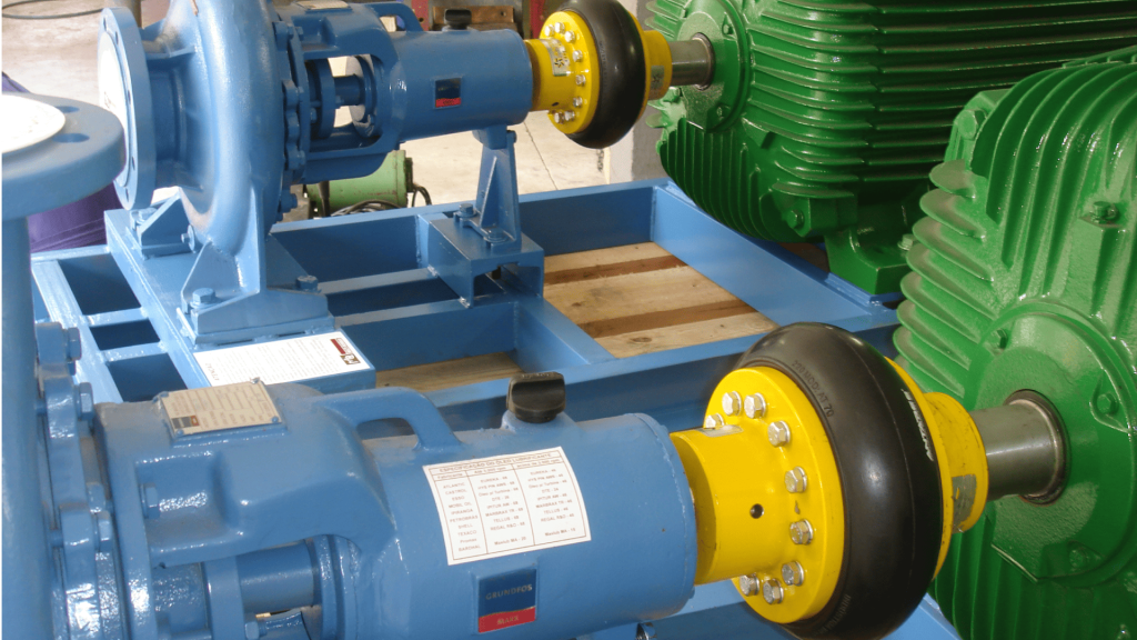 Acoplamento flexível de pneu conectando motor elétrico a bomba industrial, montado em base metálica para transmissão de torque.