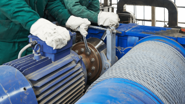 Técnicos ajustando acoplamento entre motor elétrico e redutor industrial, ambos equipamentos rotativos, garantindo alinhamento e eficiência mecânica, mostrando como melhorar o desempenho do motor.