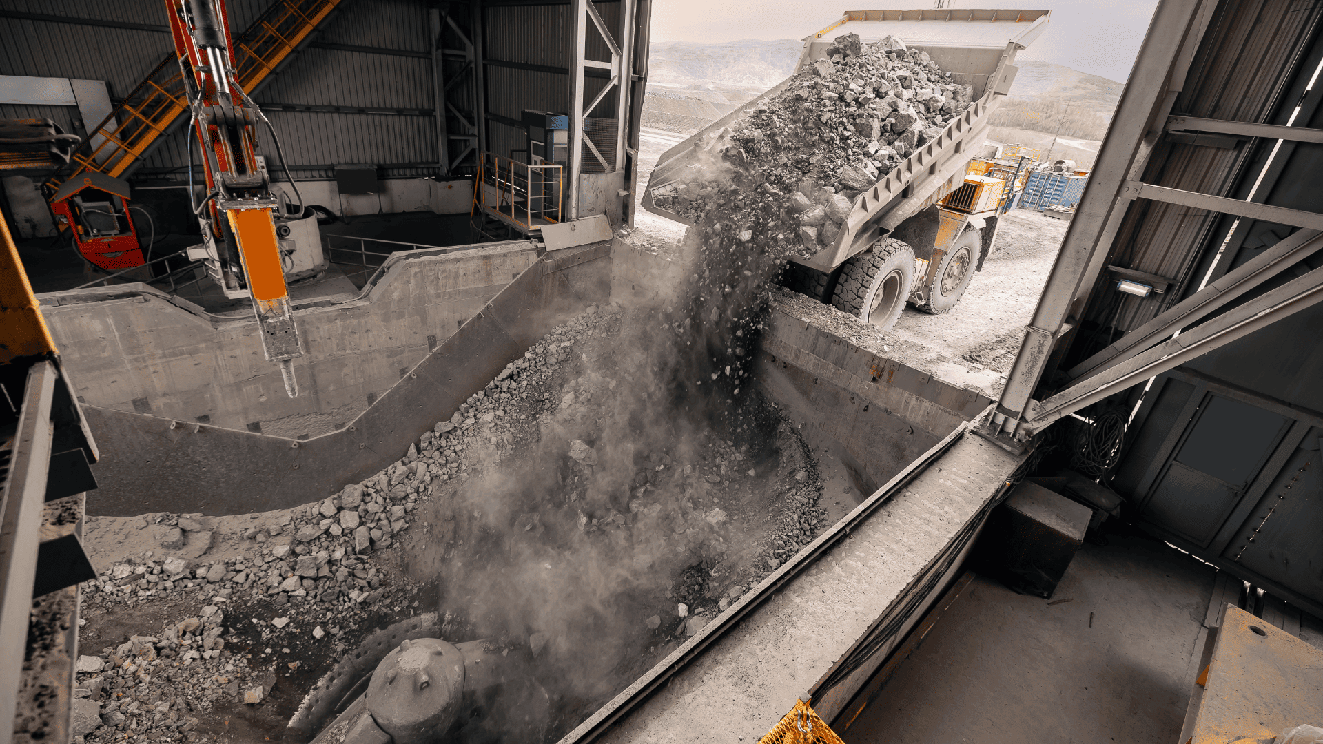 Caminhão fora de estrada descarregando rochas brutas em um britador primário; o uso de um acoplamento para britador robusto é vital para proteger o motor contra os picos de carga gerados na queda do material.