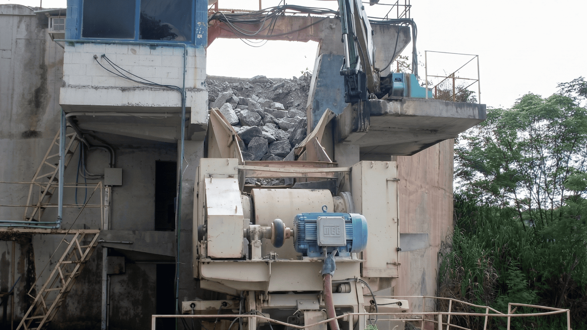 Vista frontal de motor elétrico e volante de inércia em estação de mineração, evidenciando o local de montagem do acoplamento para britador para a transferência eficiente de energia mecânica.