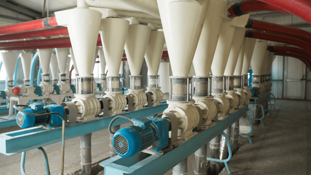 Linha de unidades de processamento com eclusas cônicas brancas e motores elétricos azuis em uma instalação de moagem. A operação contínua e eficiente dessas unidades depende de acoplamentos para moinhos de alta qualidade. Um exemplo da aplicação de acoplamentos para agronegócio.