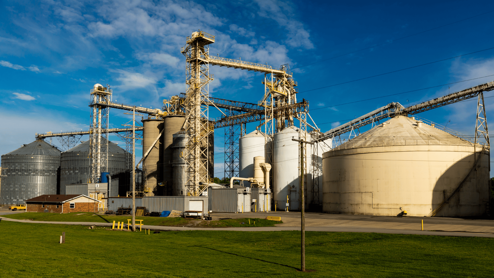 Amplo complexo industrial de armazenagem com diversos modelos de silos interconectados por esteiras transportadoras suspensas, onde o uso de acoplamentos para silos agrícolas é vital para a transmissão de potência.