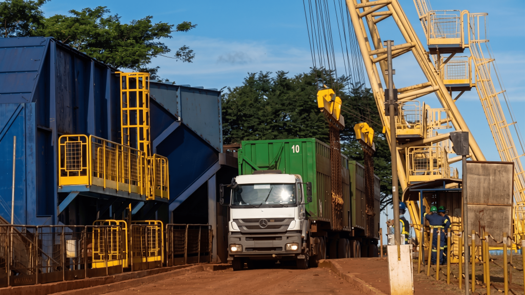 Vista de um terminal de carga industrial com um caminhão de contêiner e uma grande grua amarela, um ambiente típico onde o acoplamento elástico para torque alto é essencial para operar máquinas de manuseio de material pesado e sistemas de transmissão.