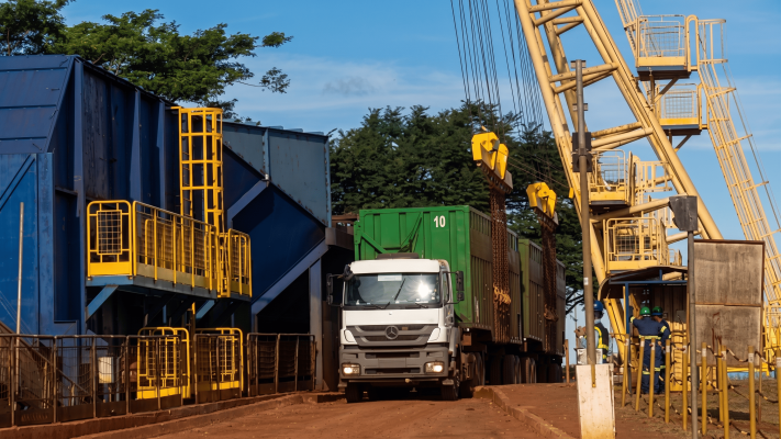 Vista de um terminal de carga industrial com um caminhão de contêiner e uma grande grua amarela, um ambiente típico onde o acoplamento elástico para torque alto é essencial para operar máquinas de manuseio de material pesado e sistemas de transmissão.